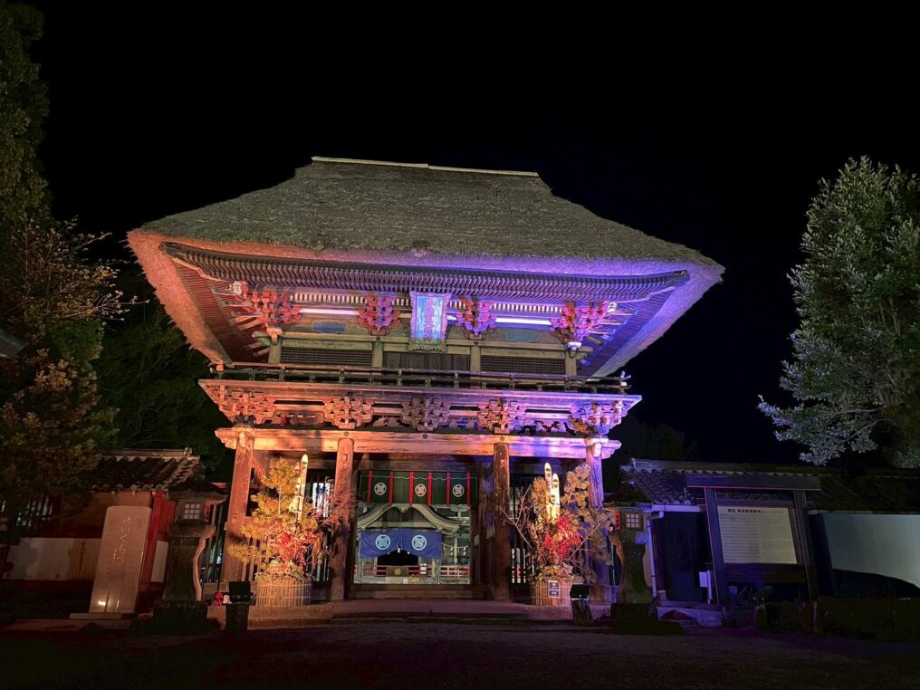 夜間に紫色の光でライトアップされた国宝 青井阿蘇神社の楼門