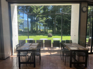 南阿蘇の絶景カフェ「白水郷アートプレイス」の大きな窓から見える、開放的なガーデンとテラス席