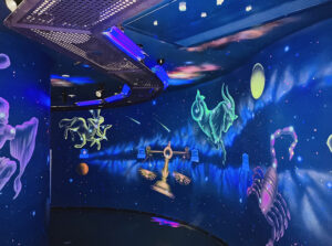 ミューイ天文台内のプラネタリウムまたは展示室。星座や惑星のイラストが壁一面に描かれ、宇宙空間を再現している。